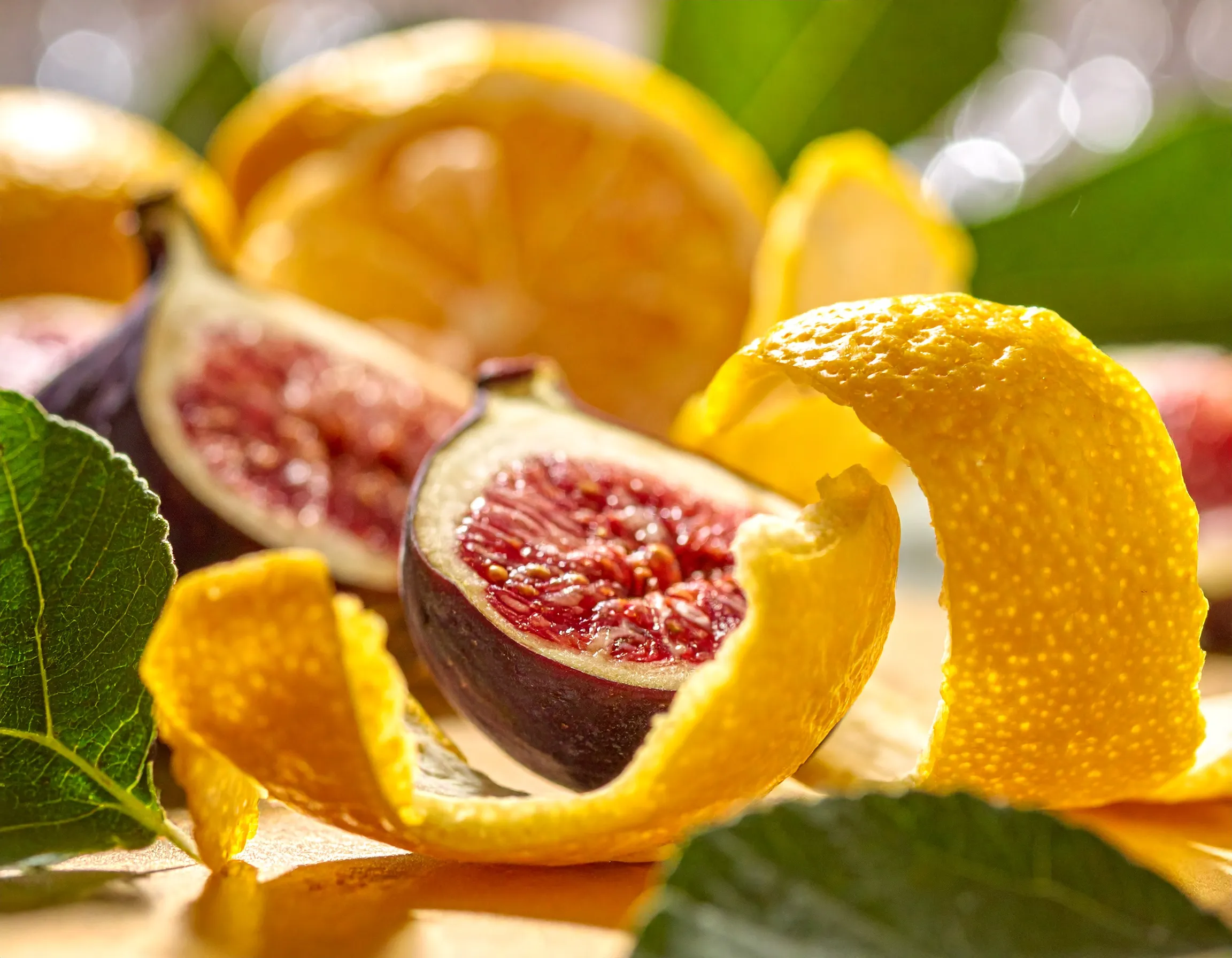 Macro view of a sliced ripe fig nestled in curling yuzu peel beside a fig leaf